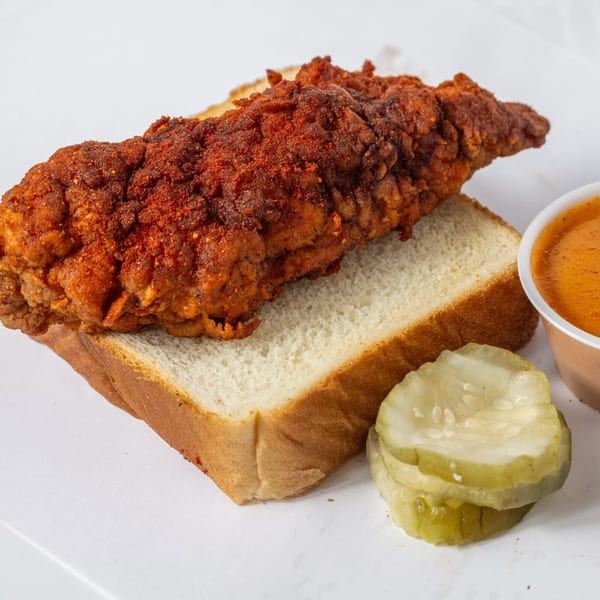 Hot Birds' fried chicken tender on white bread with pickles and dipping sauce.