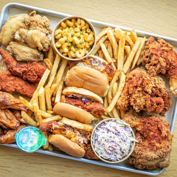 A large tray of Hot Birds fried chicken, fries, mac and cheese, coleslaw, and chicken sandwiches.