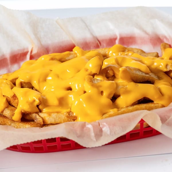 Hot Birds' crispy golden fries generously topped with melted yellow cheese sauce in a red basket.